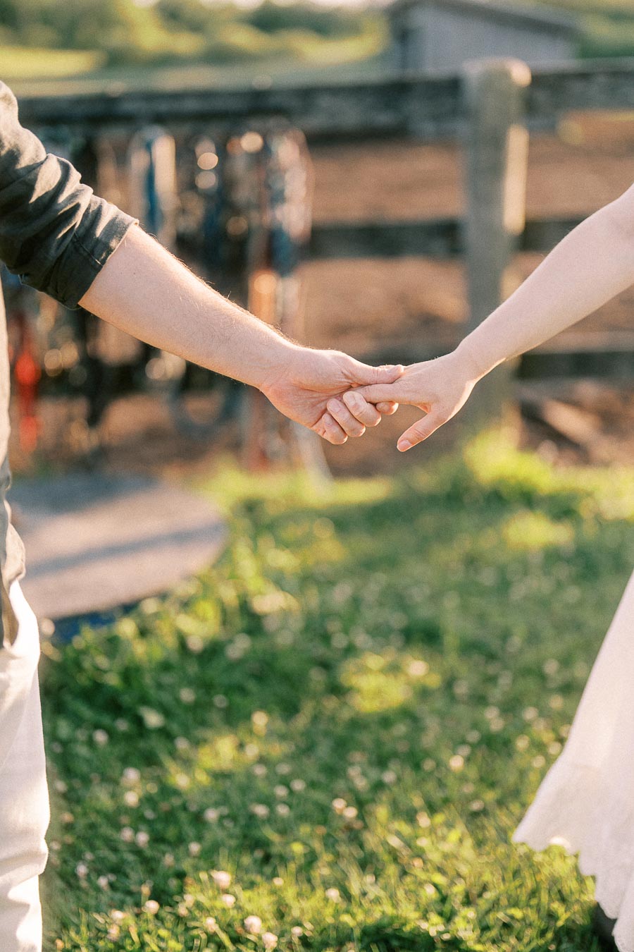 Couple holding hands in a grassy farm setting at The Green Acres