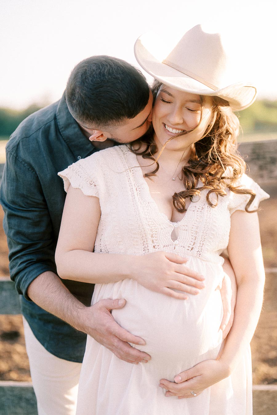 Expectant couple embracing in a sunlit farm maternity portrait