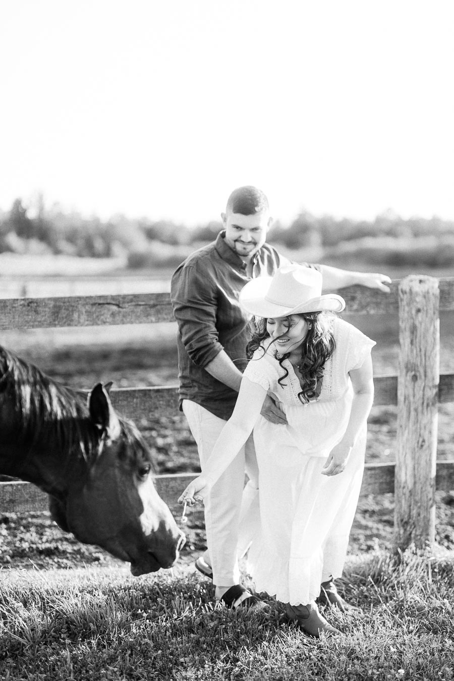 Expectant couple in a paddock feeding a horse at The Green Acres