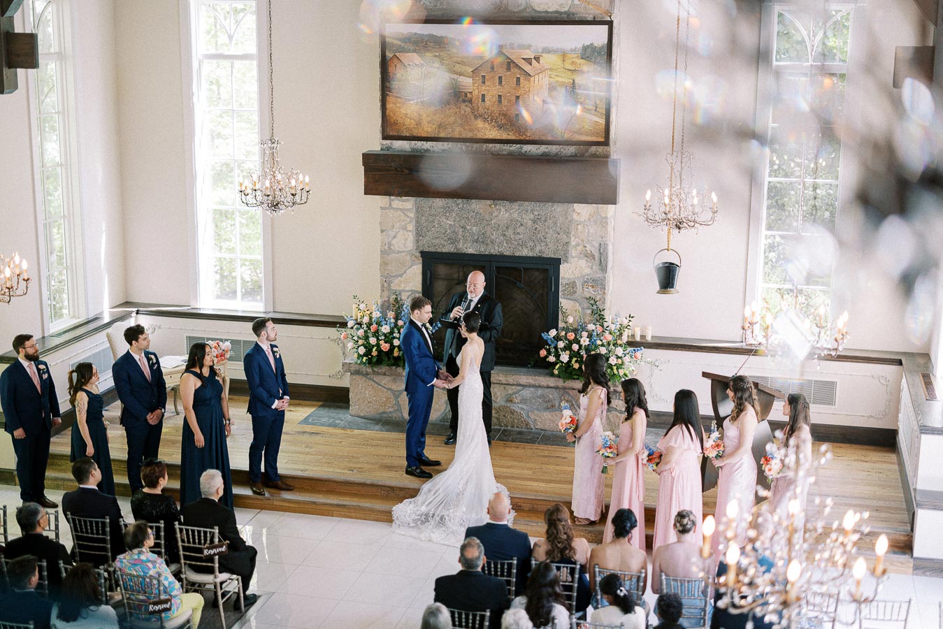Miffy and Rawle stand at the altar with their wedding party during an indoor ceremony at Ancaster Mill.
