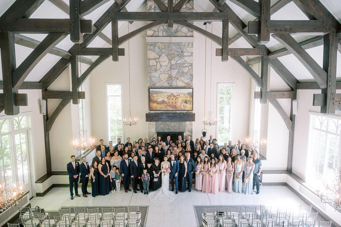 Large wedding group portrait with the couple and guests inside a timber-framed chapel at Ancaster Mill