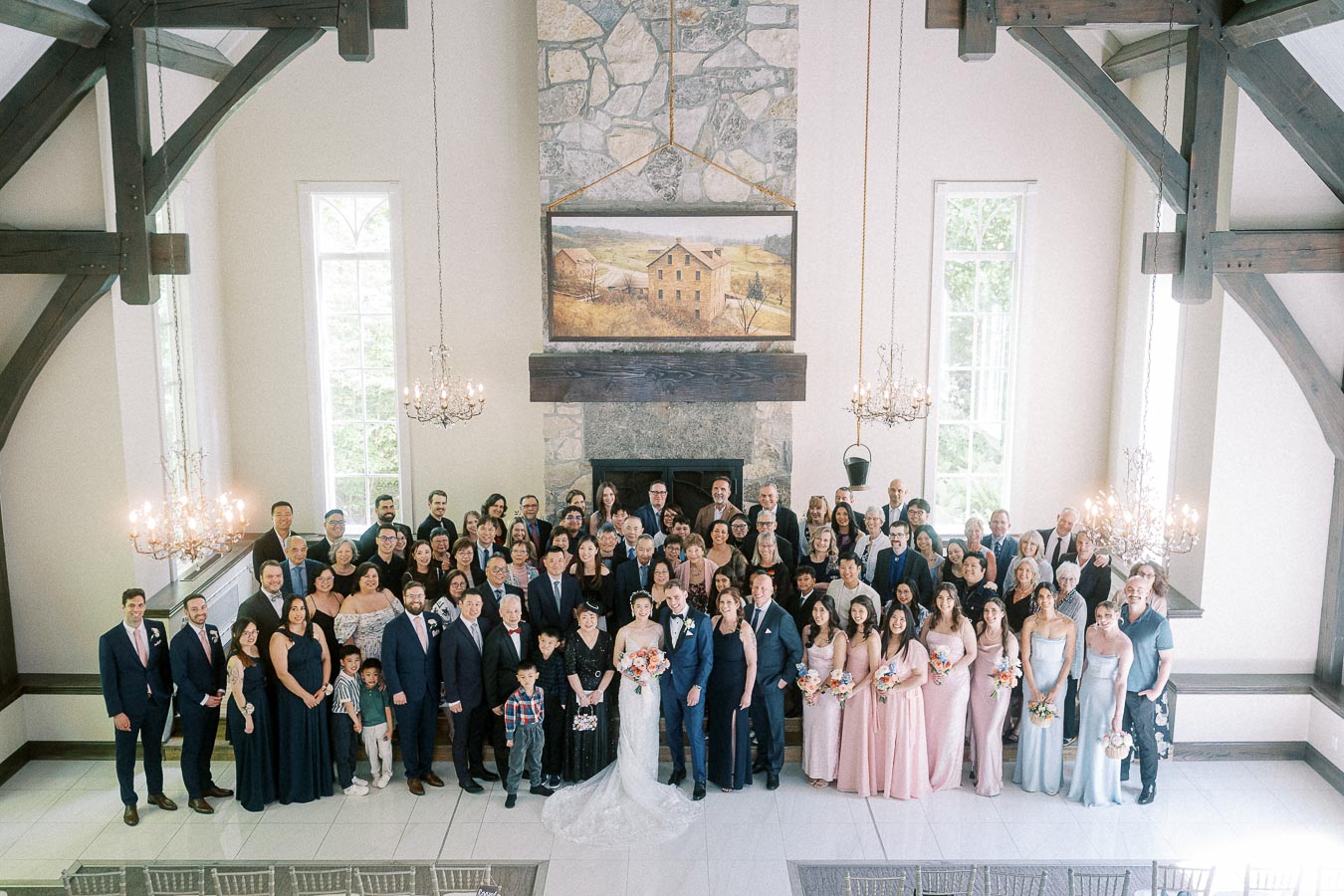 Large wedding group portrait inside Ancaster Mill chapel with Miffy and Rawle centered among guests