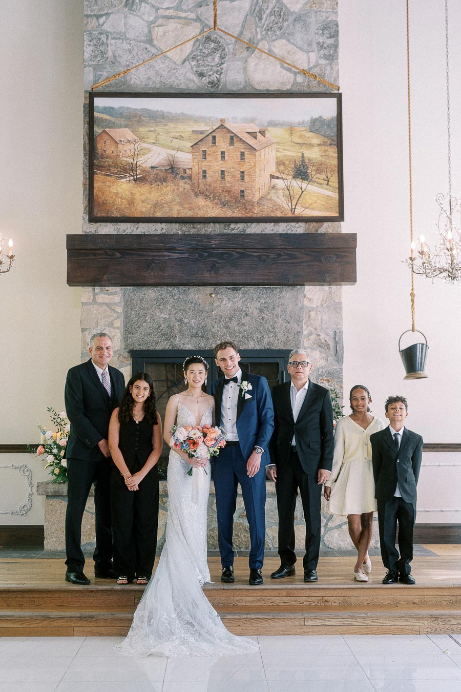 Miffy and Rawle stand with five family members in front of a stone fireplace at Ancaster Mill.