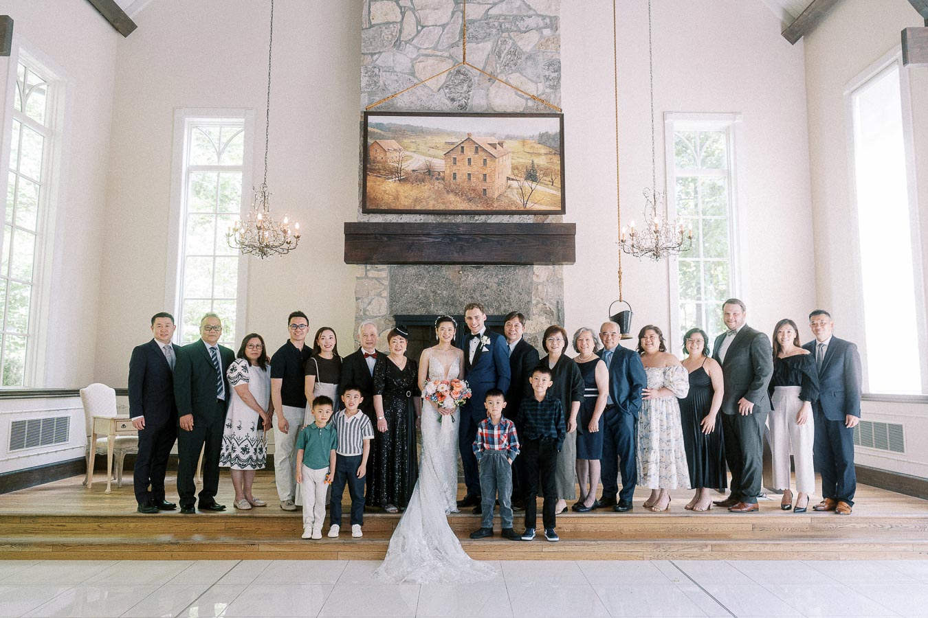 Miffy and Rawle pose with family indoors before a stone fireplace and chandeliers at Ancaster Mill.