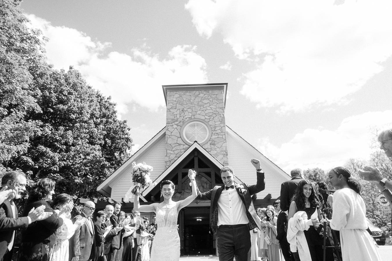 Miffy and Rawle raise their arms as guests cheer outside the stone chapel at Ancaster Mill.