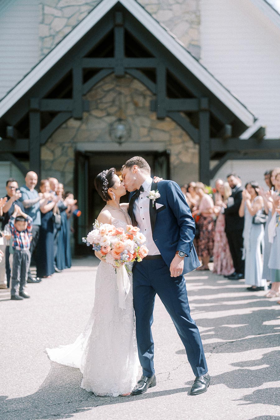 Miffy and Rawle kiss outside Ancaster Mill chapel as guests clap along the walkway.