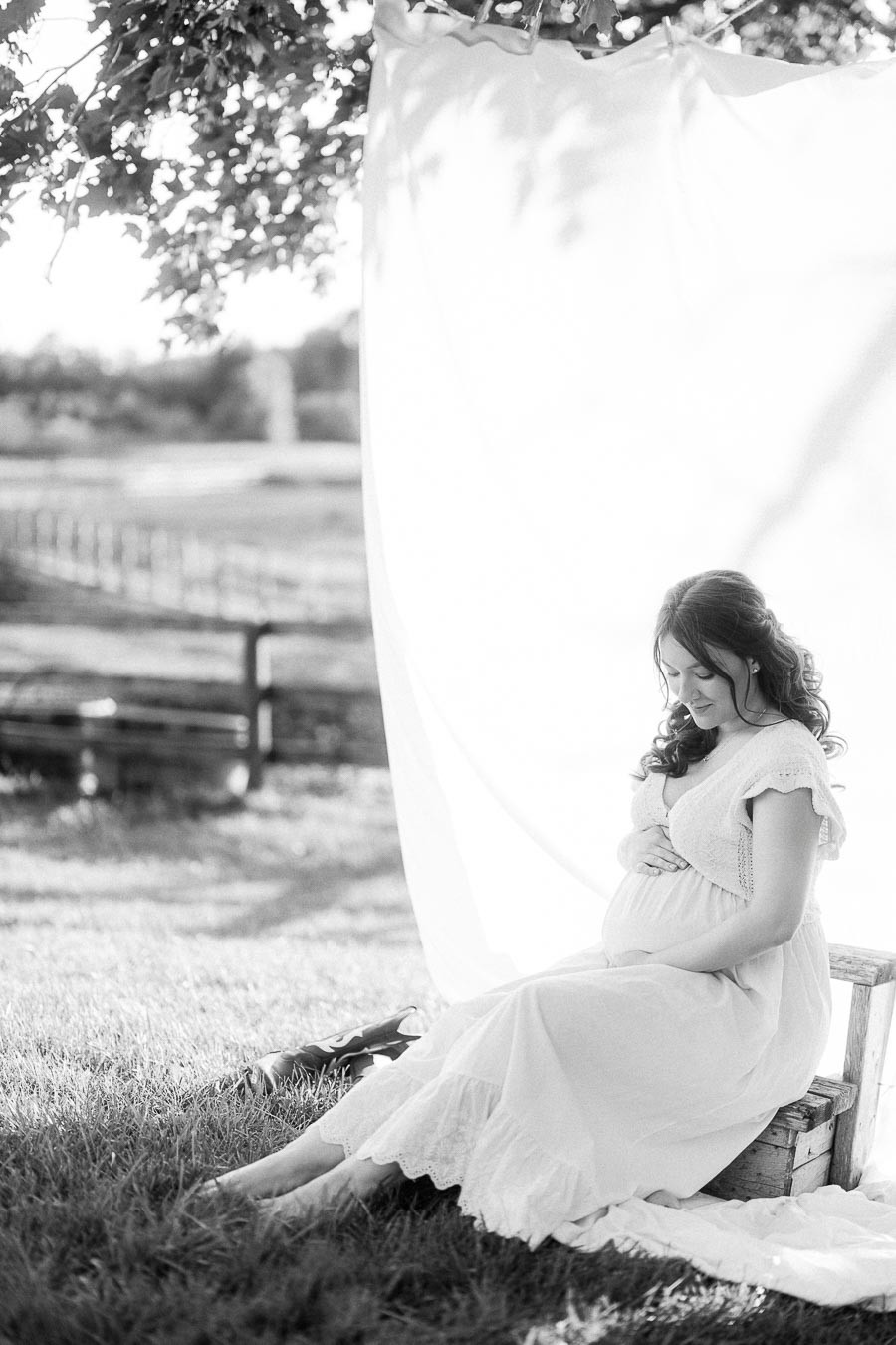 Pregnant woman seated on a bench under a white drape at The Green Acres
