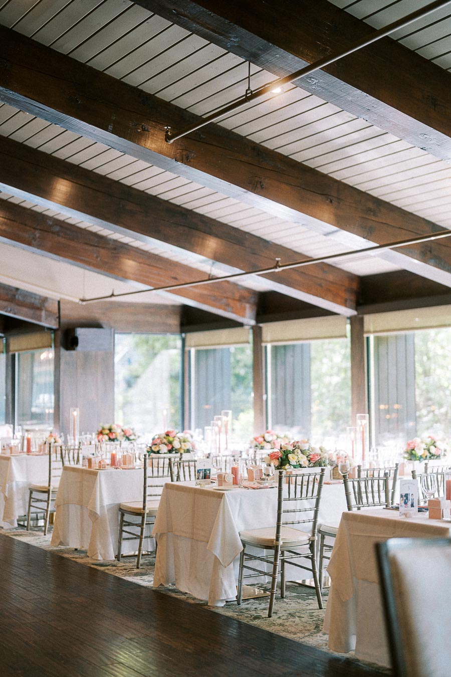 Elegant wedding reception tables with floral centerpieces under exposed wooden beams at Ancaster Mill