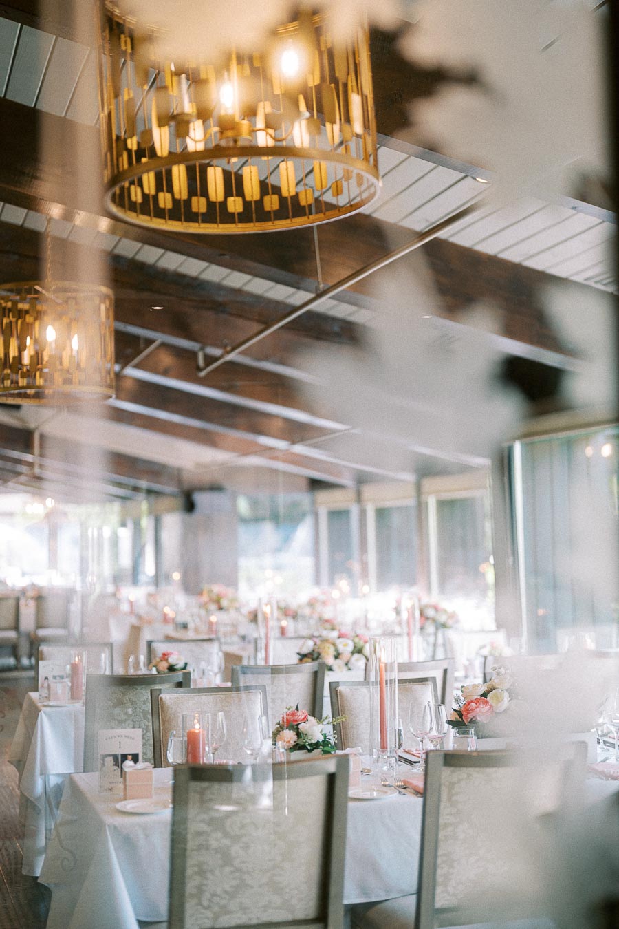 Ancaster Mill reception room with round tables, floral centrepieces, taper candles, and chandeliers overhead