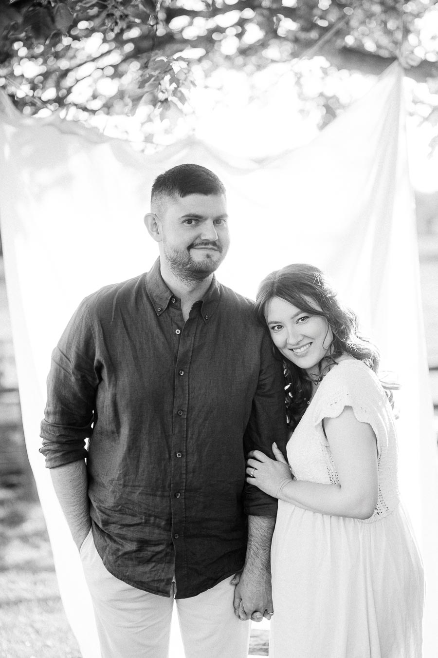 Expectant couple standing together beneath trees at The Green Acres
