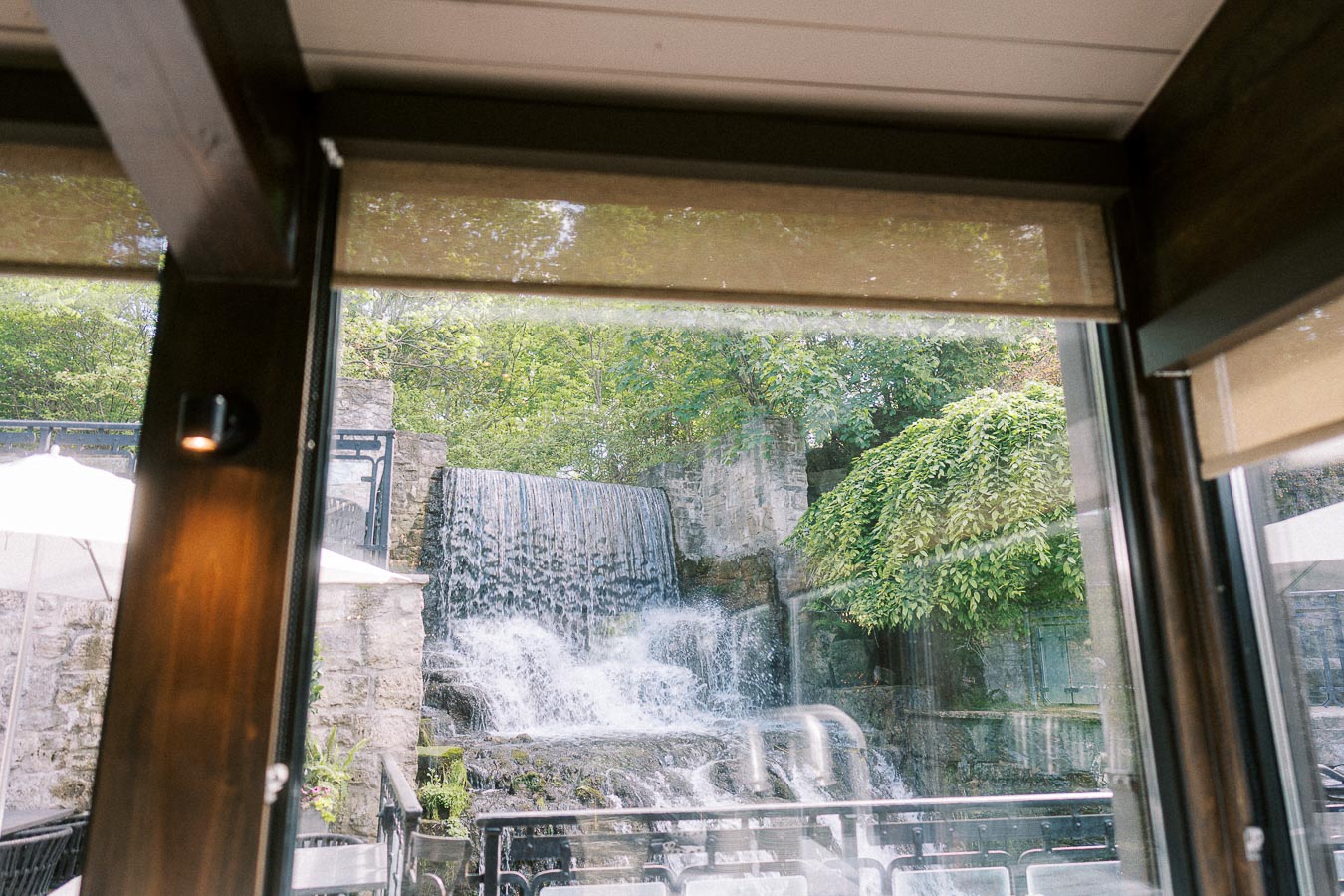 Waterfall and stone walls seen through large windows at Ancaster Mill in Ontario.