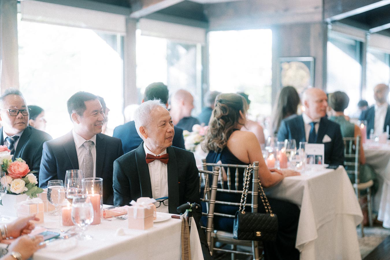 Wedding guests in formal attire seated at candlelit reception tables inside Ancaster Mill