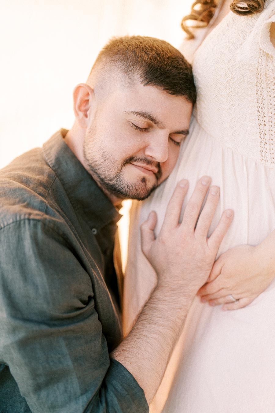 Expectant father resting his head against a pregnant belly