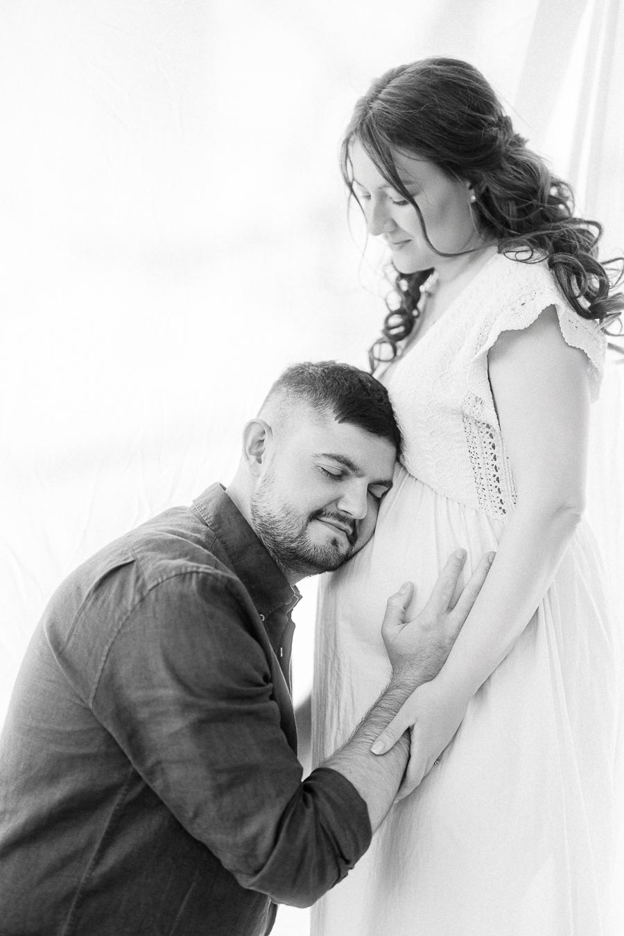 Expectant couple sharing a quiet maternity portrait in soft black and white