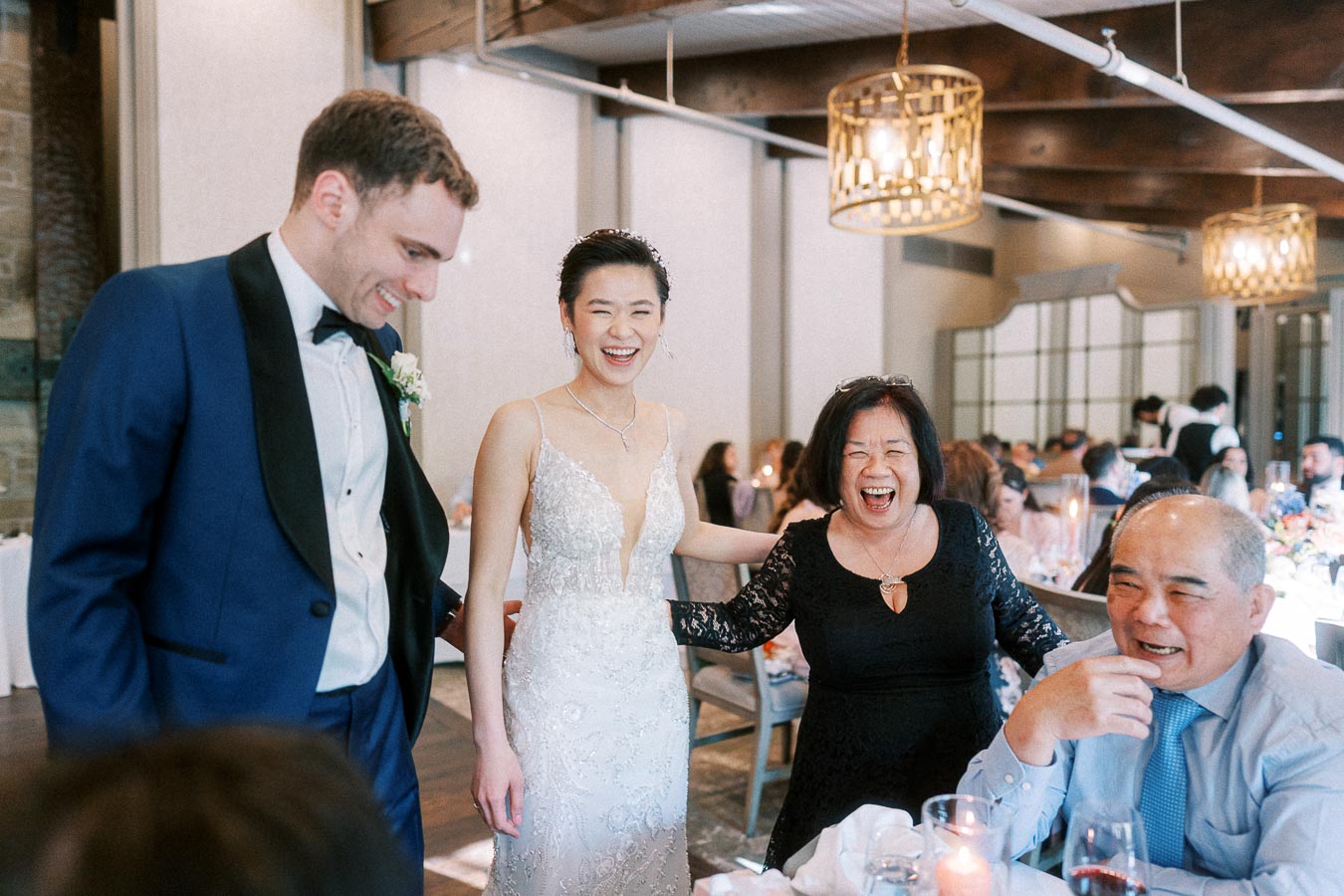 Miffy and Rawle laugh with seated wedding guests during their reception at Ancaster Mill.