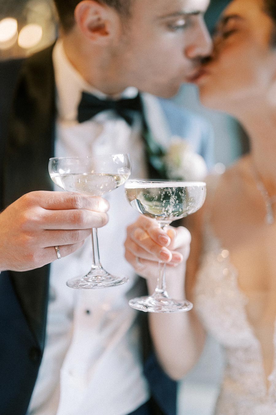 Newlywed couple sharing a kiss while toasting with champagne glasses, highlighting a romantic wedding celebration.