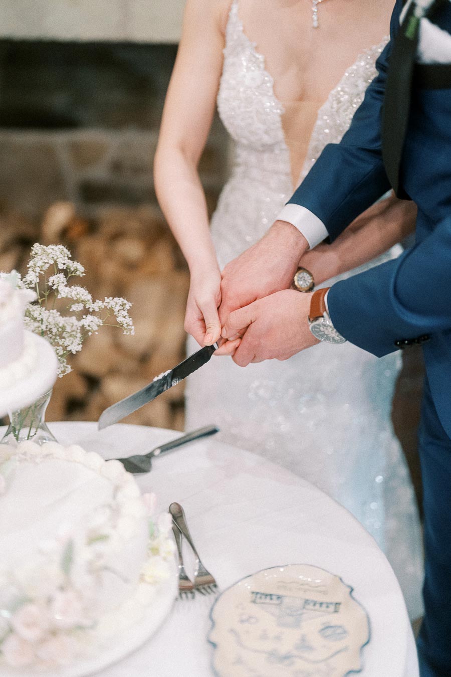 A bride and groom in elegant attire cut a wedding cake together, symbolizing unity and celebration at their wedding reception.