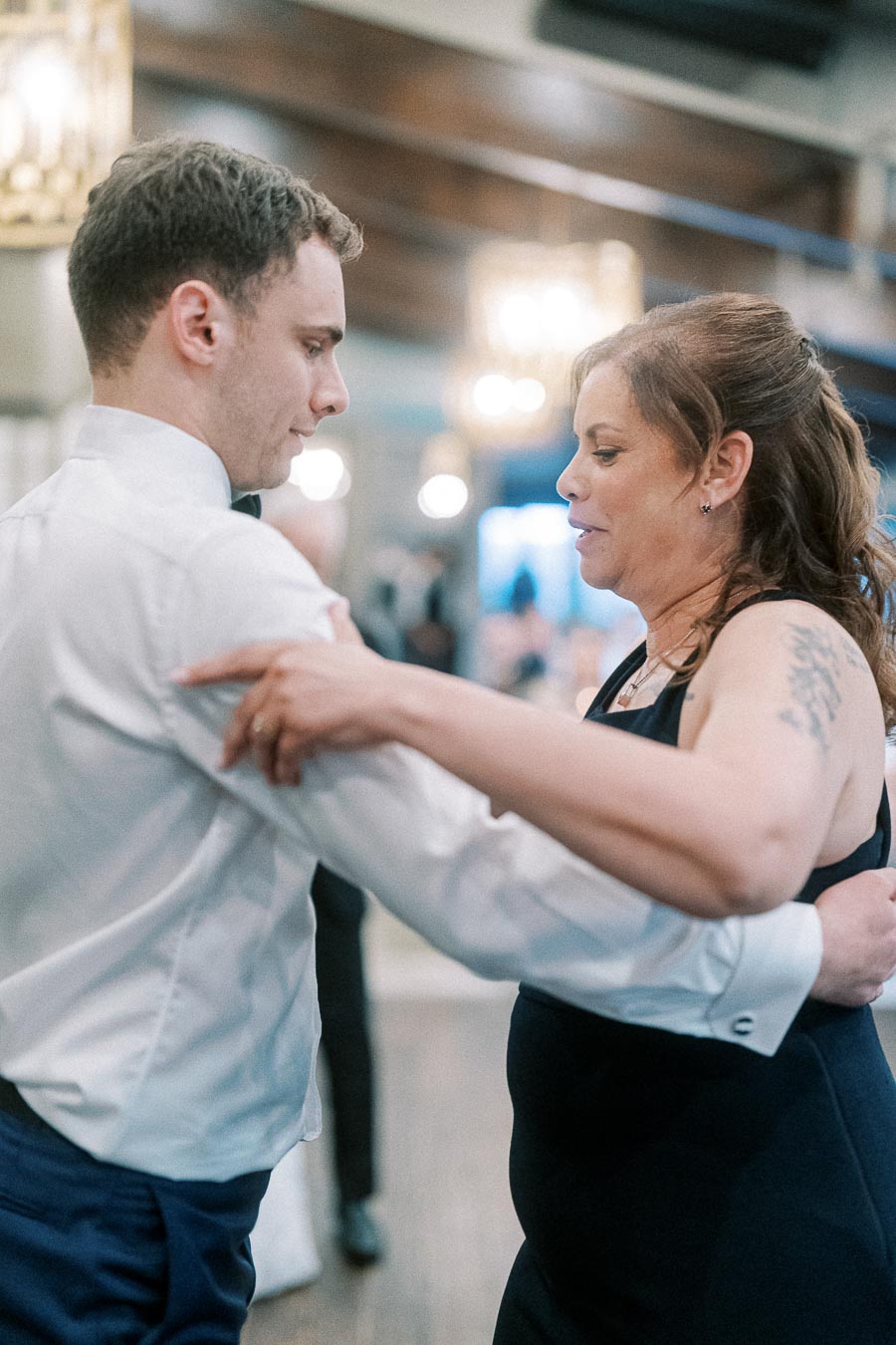 Man and woman dancing closely at an indoor event, capturing a moment of connection and elegance.