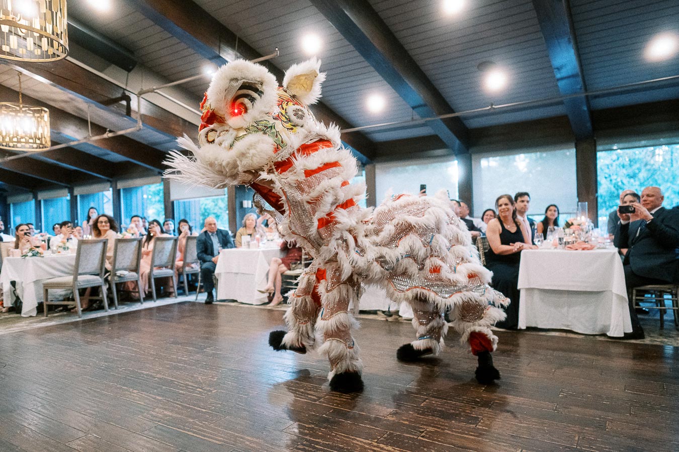 Traditional Chinese lion dance performance at an indoor event, captivating an audience seated at elegantly decorated tables.