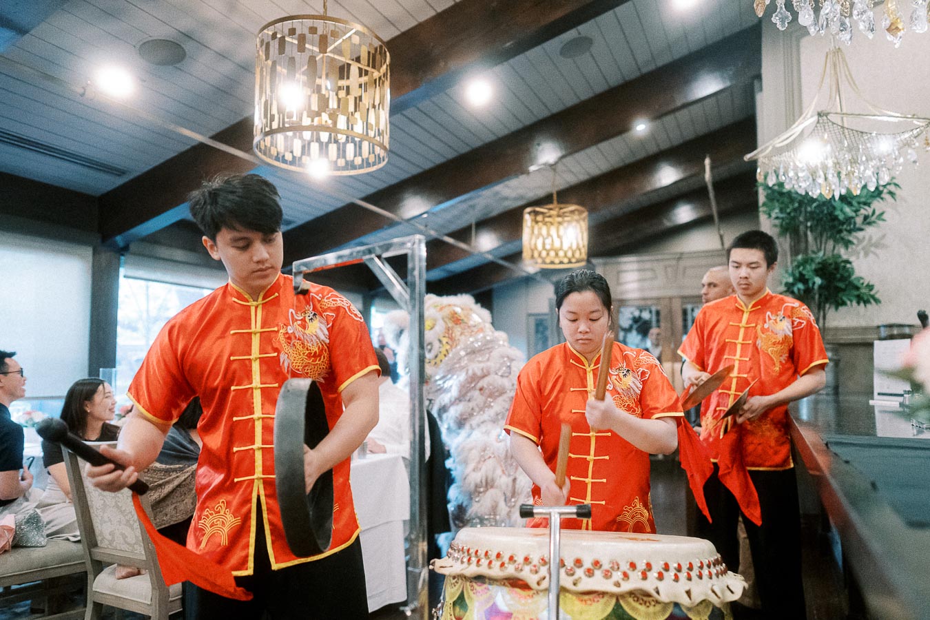 Traditional Lion Dance Performance Indoors with Musicians in Red Attire Playing Drums and Cymbals