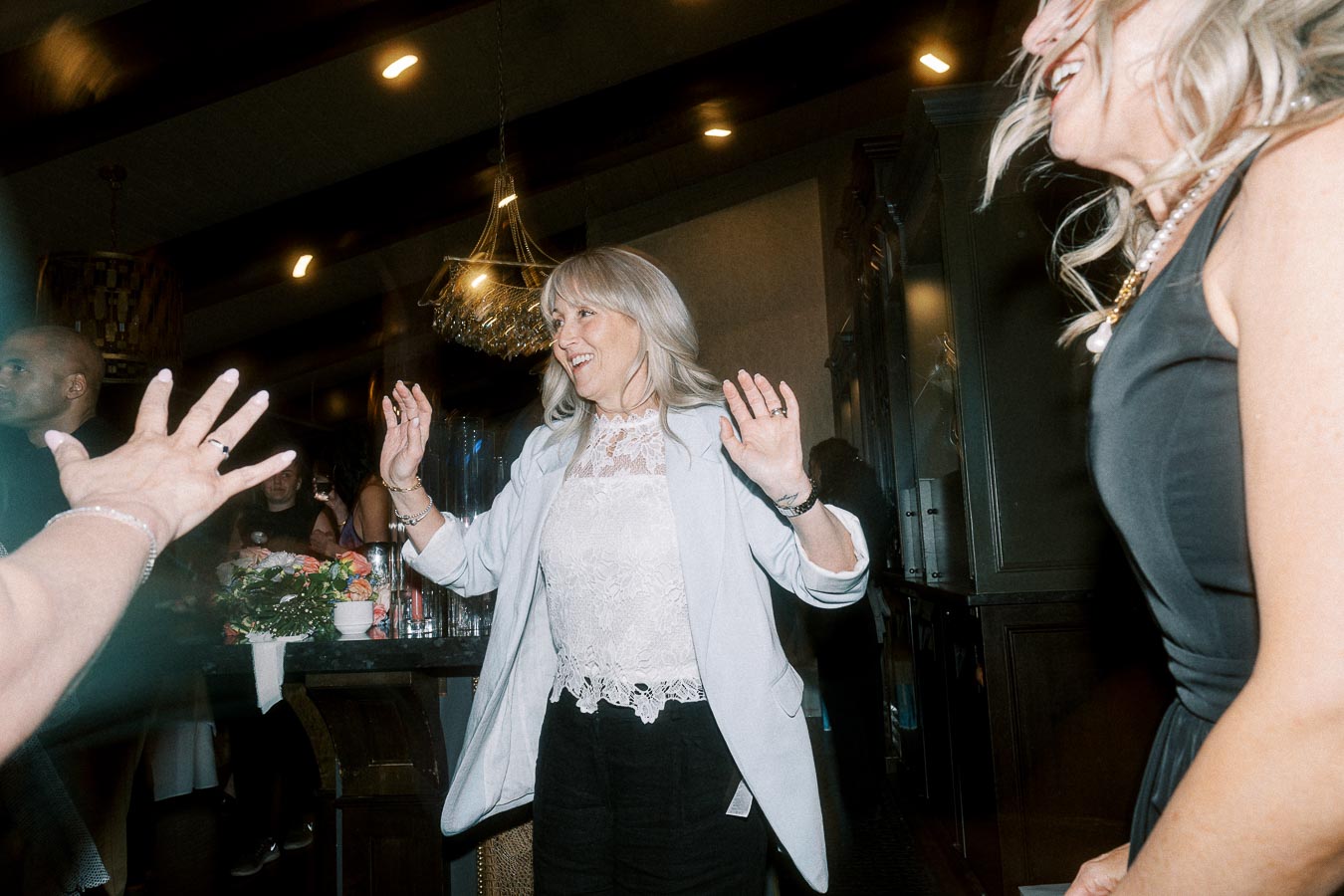 Women joyfully dancing at a lively indoor event, surrounded by elegant decor and soft lighting.