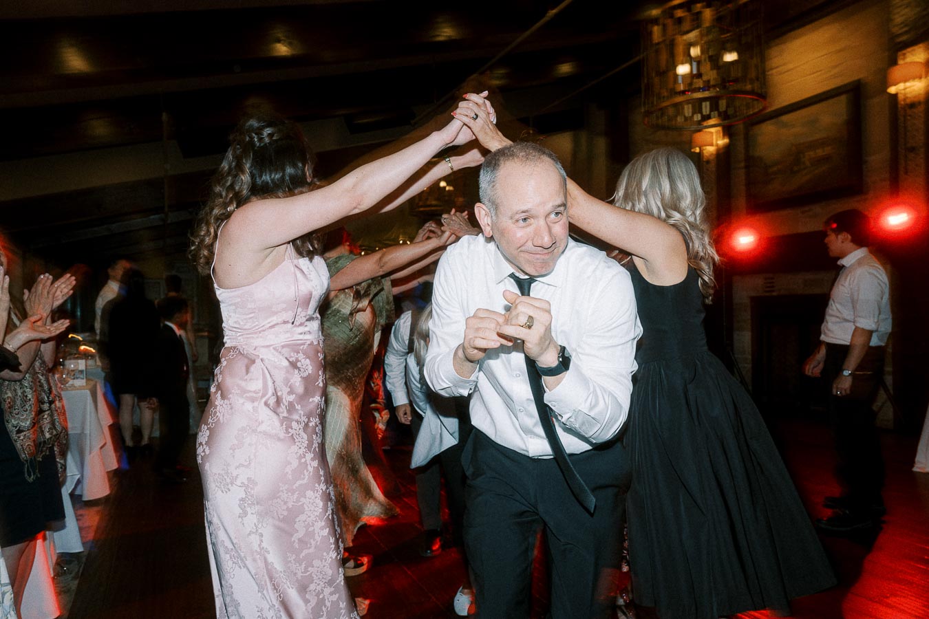 A lively wedding reception with guests joyfully dancing and celebrating, highlighting the festive atmosphere and elegant evening attire.