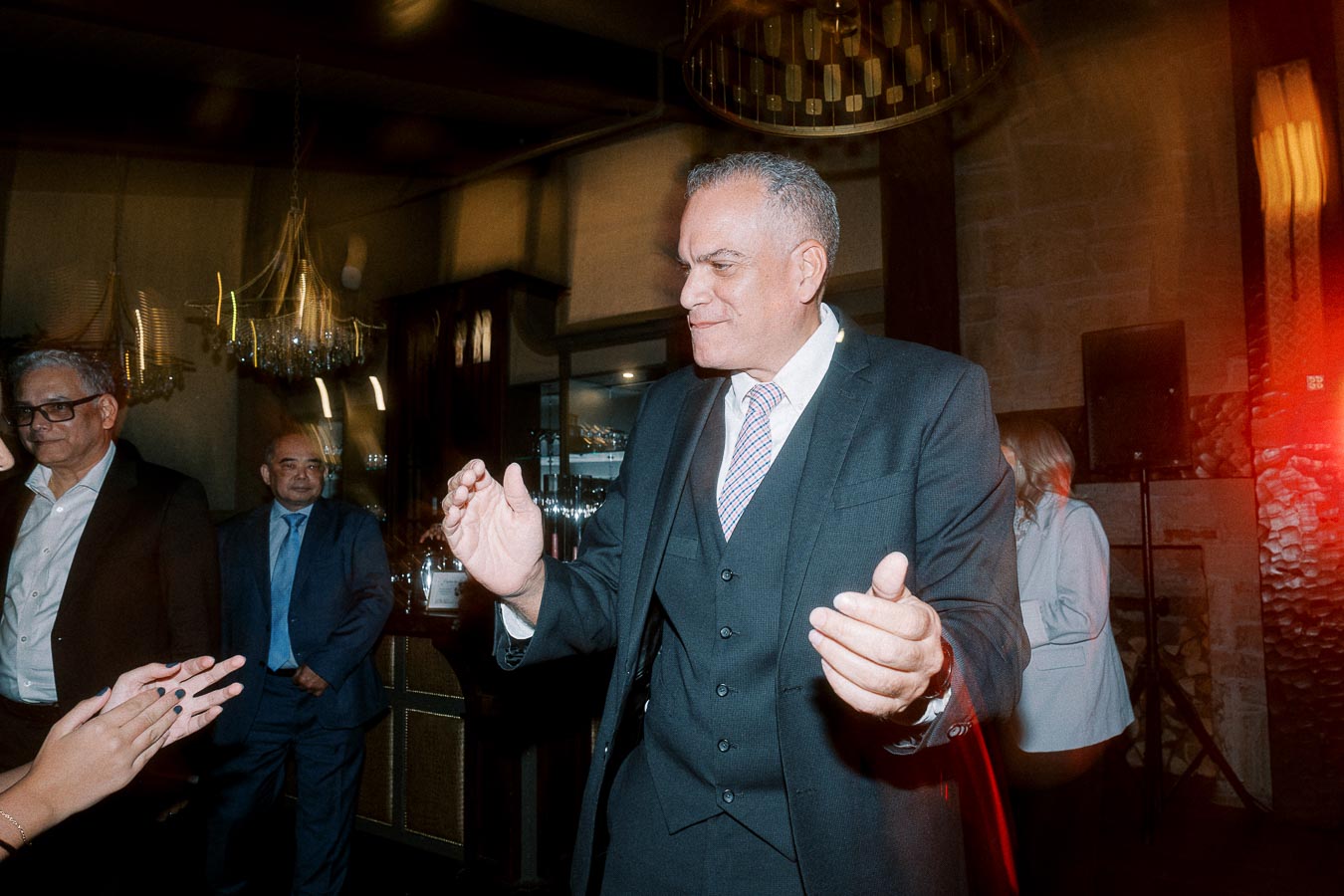 A group of people in formal attire enjoying a lively social event inside a dimly lit venue.