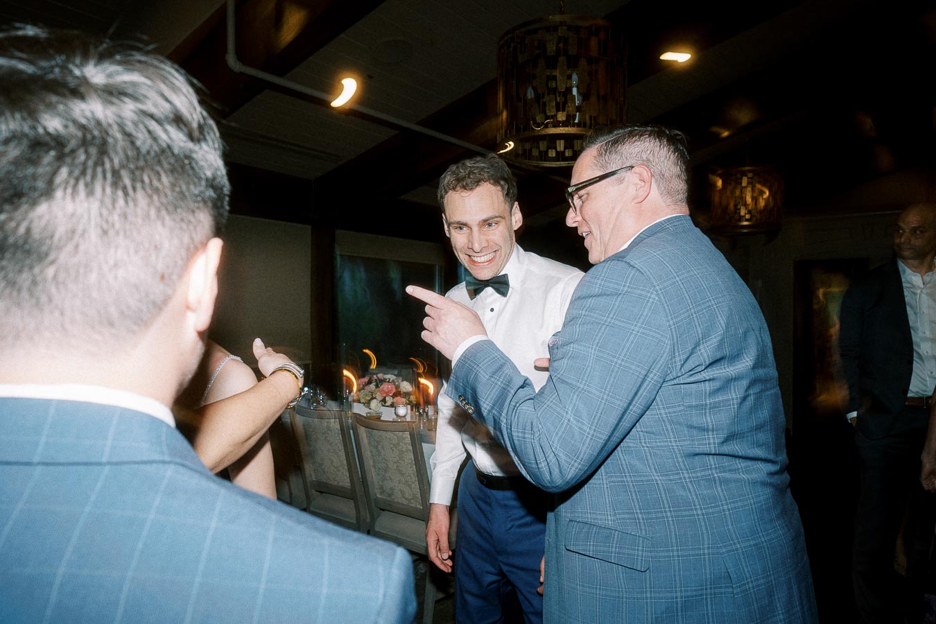 Group of people in formal attire engaging in lively conversation at an indoor event.