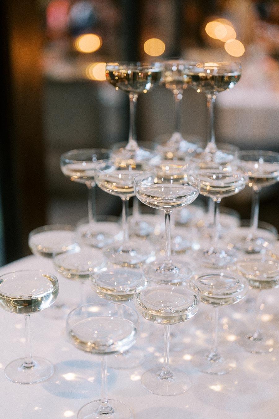 A cascading champagne tower with elegant coupe glasses filled with bubbly champagne, creating a festive and luxurious celebration atmosphere.