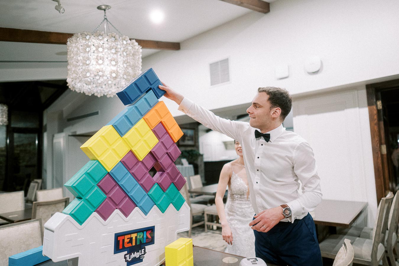 Man in formal attire playing a giant Tetris game at an indoor event, emphasizing fun and interaction.