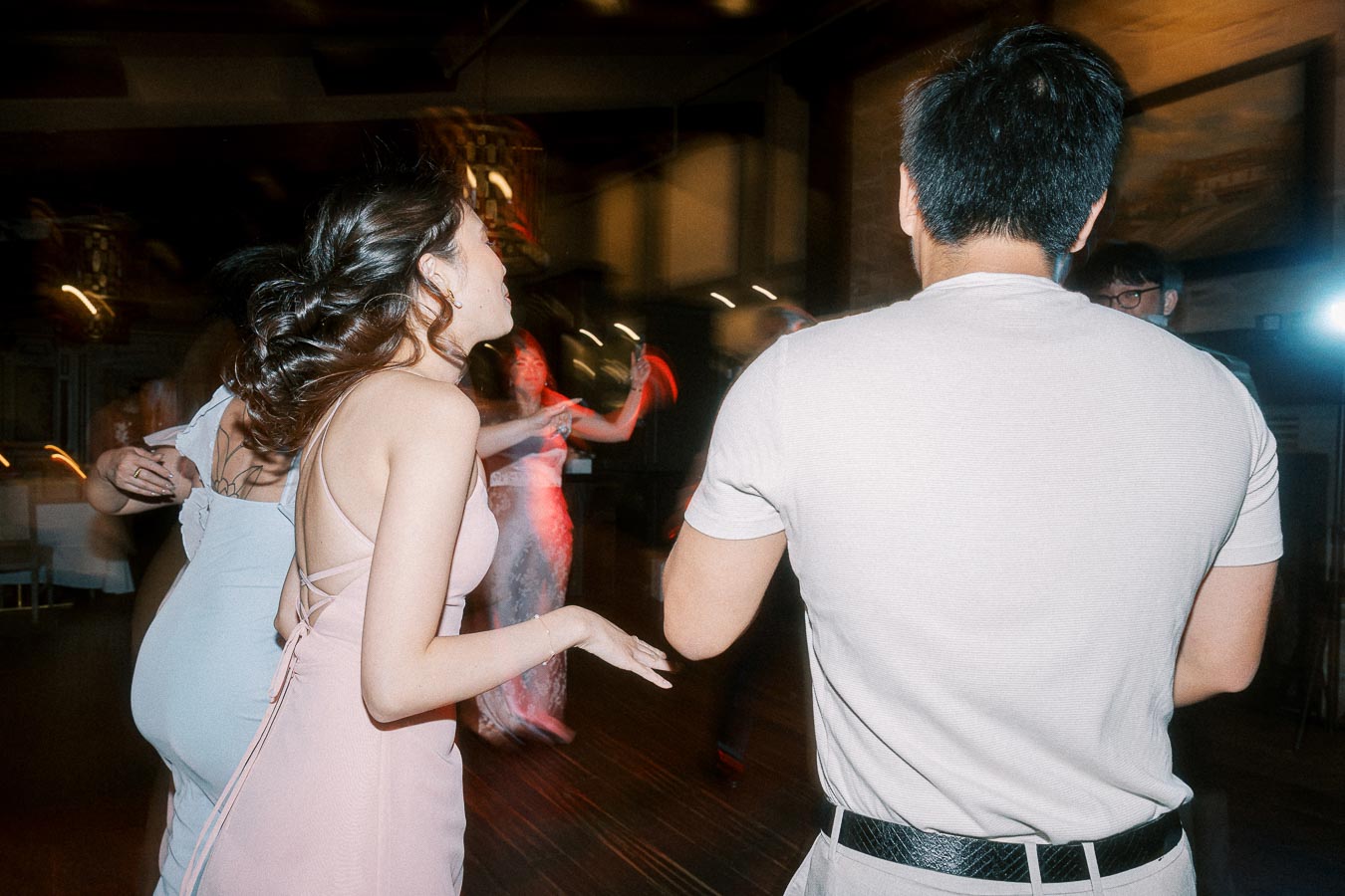 People dancing energetically at a lively indoor party, wearing stylish evening attire, with blurred motion capturing the essence of fun and celebration.