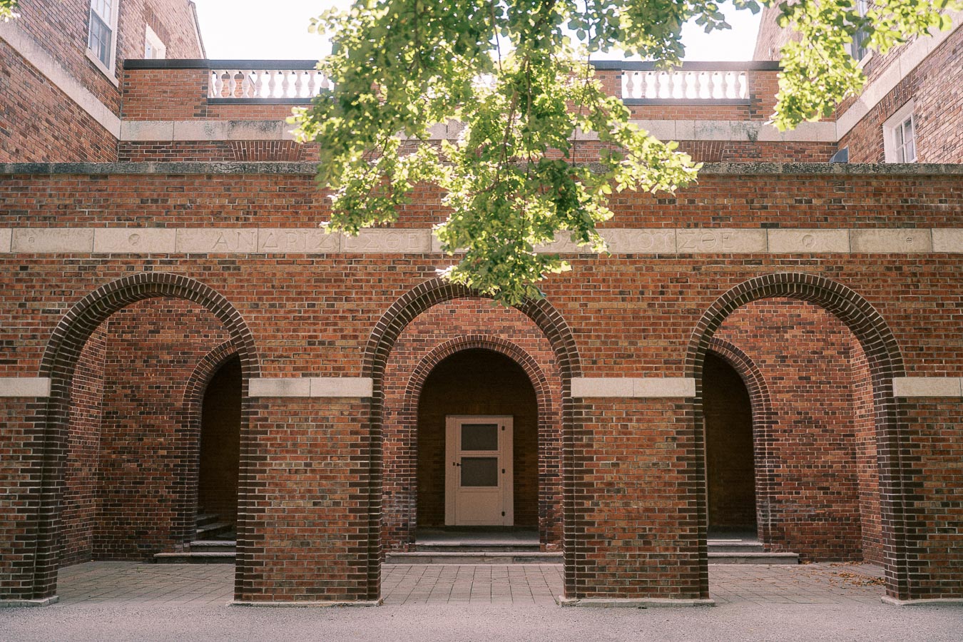 Brick courtyard with three arched openings and leafy branches overhead in Aurora, Ontario.