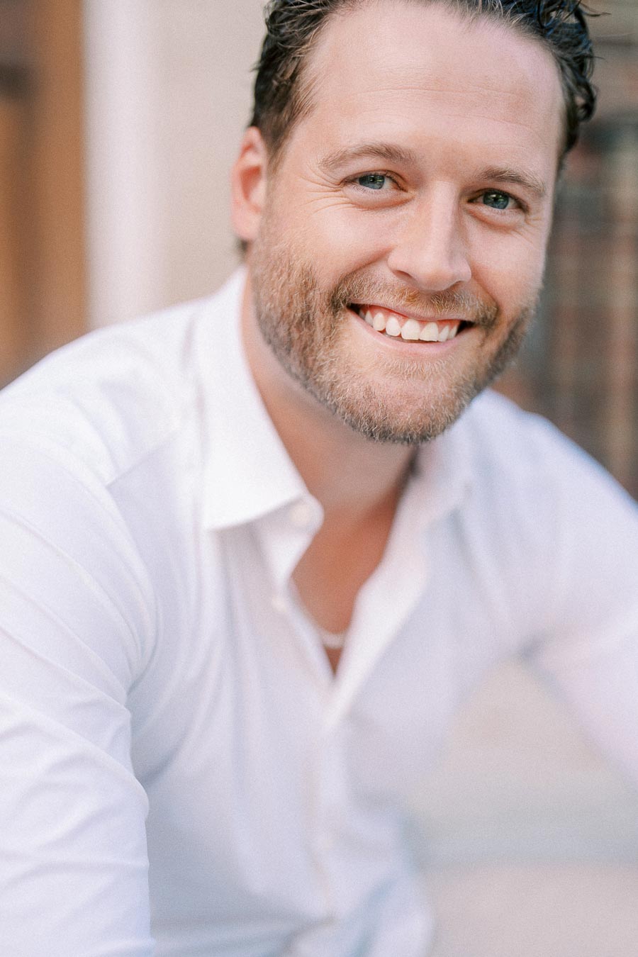 Matt smiles warmly in a close-up portrait, wearing a white shirt against a softly blurred background.