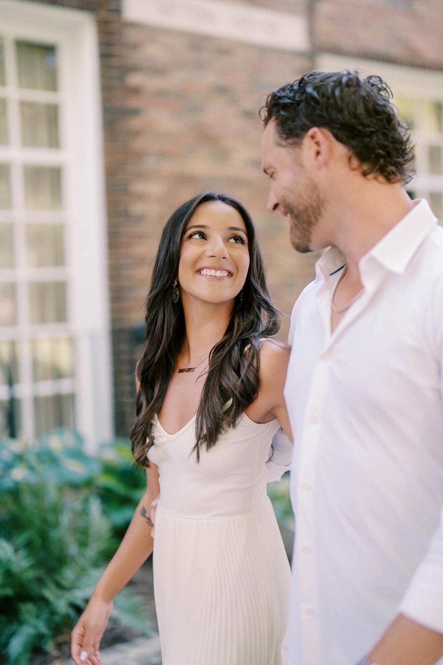 Rachel smiles up at Matt as they walk together beside a brick building in Aurora, Ontario.