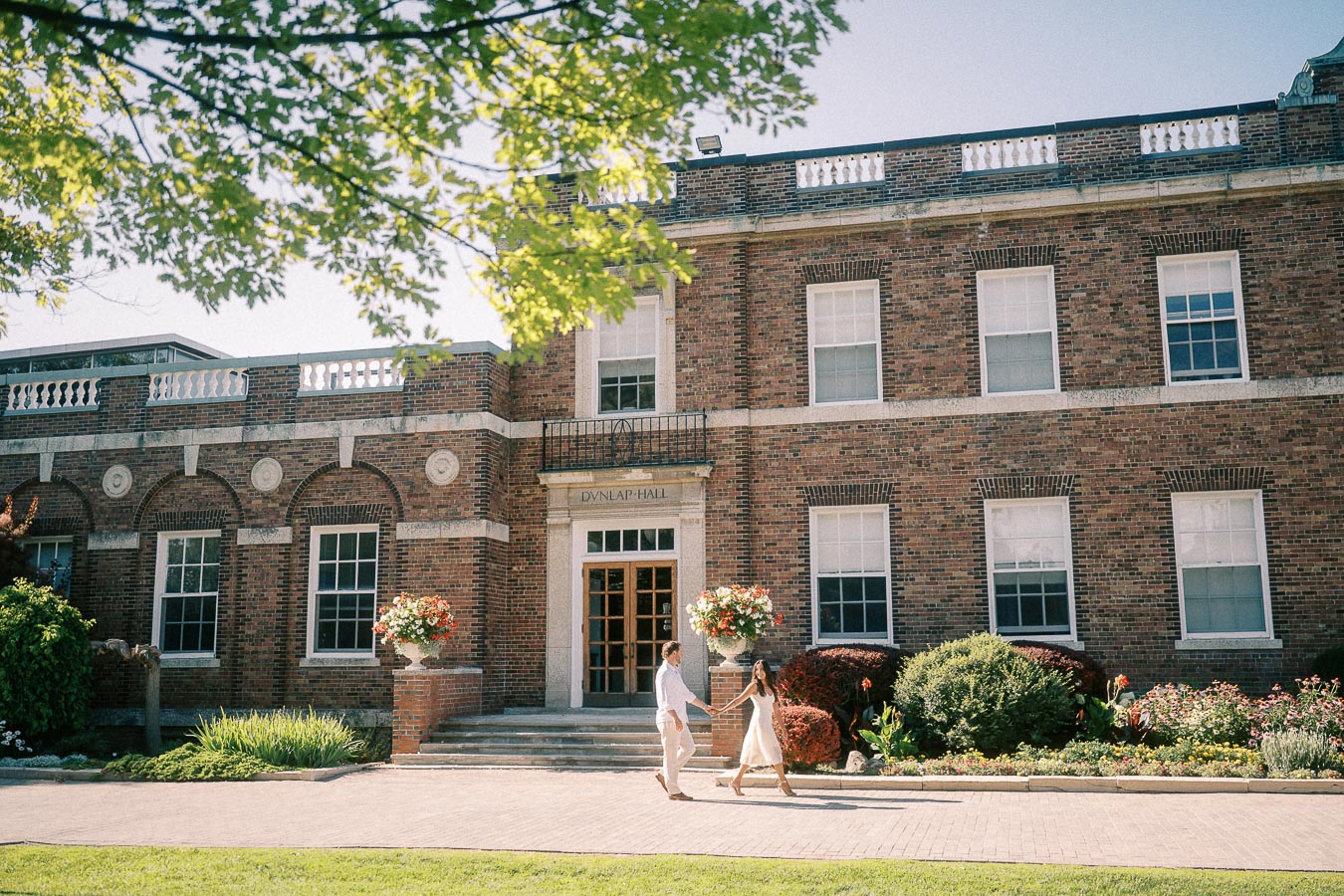 Rachel and Matt walk hand in hand in front of Dunlap Hall at St. Andrew’s College.