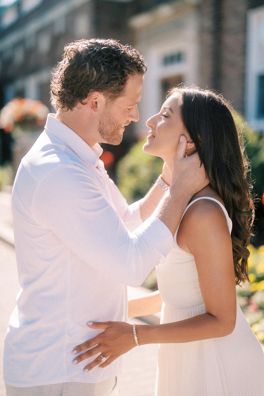 Matt gently holds Rachel’s face as they smile closely together outside a brick building in Aurora.