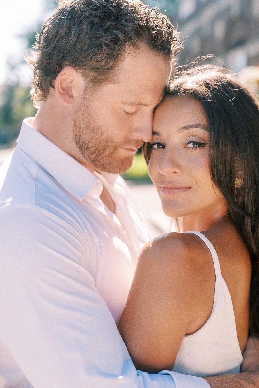Rachel and Matt embrace closely outdoors in bright sunlight during their engagement session in Aurora.