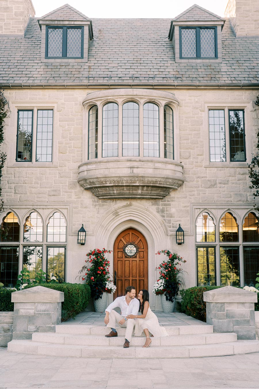 Rachel and Matt sit close together on stone steps beneath an arched doorway of a historic building.