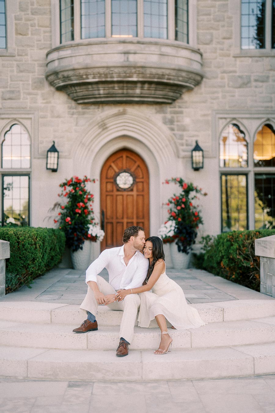 Rachel and Matt sit closely on stone steps beneath an arched doorway at St. Andrew’s College.