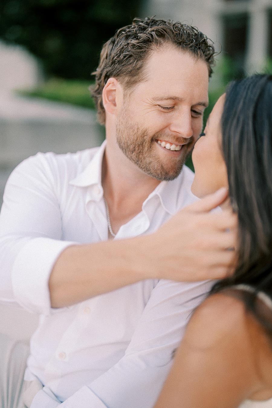 Matt smiles warmly while holding Rachel close during their outdoor engagement portrait in Aurora.