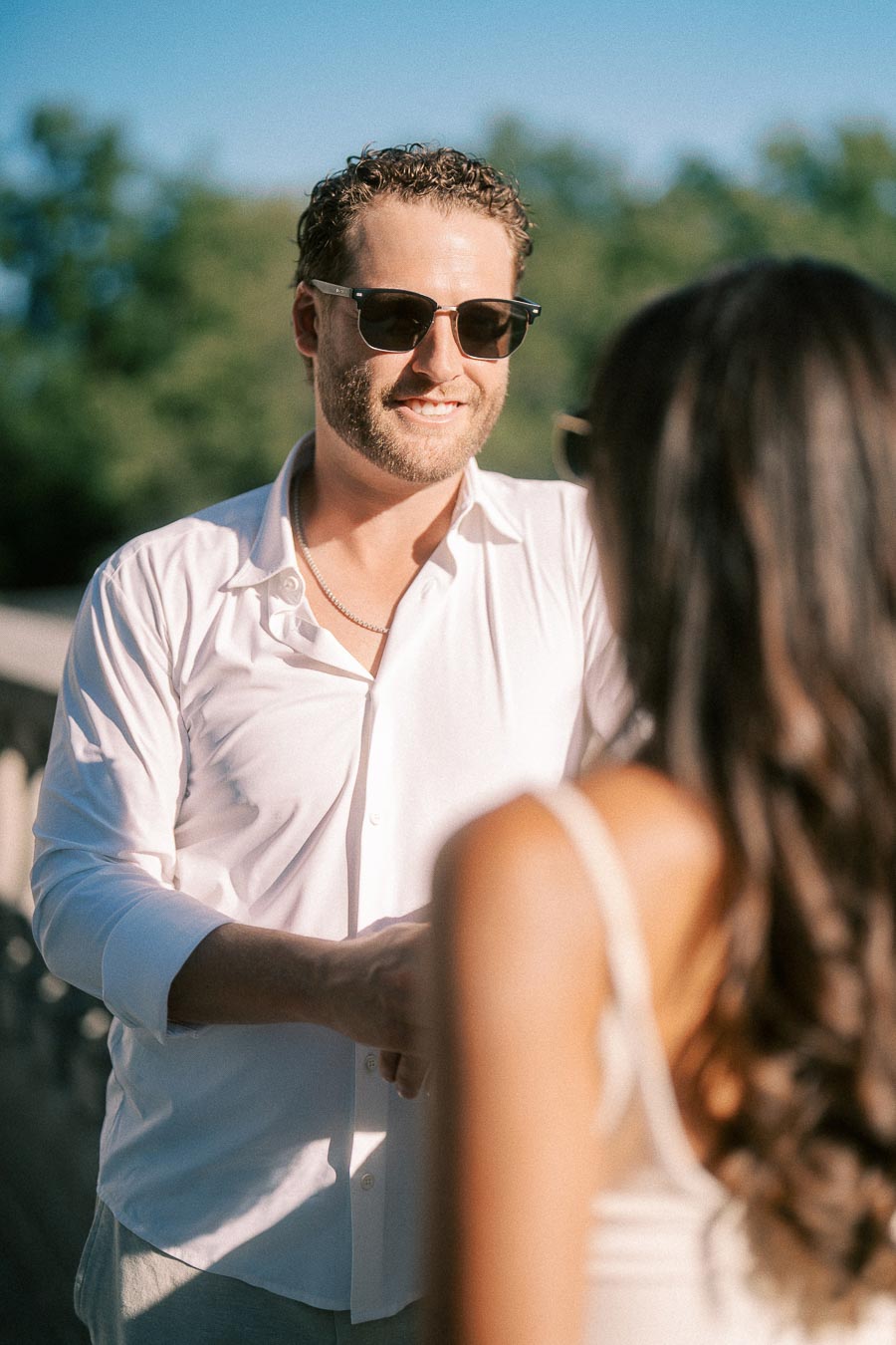 Matt smiles in sunglasses while facing Rachel outdoors in warm sunlight in Aurora, Ontario.