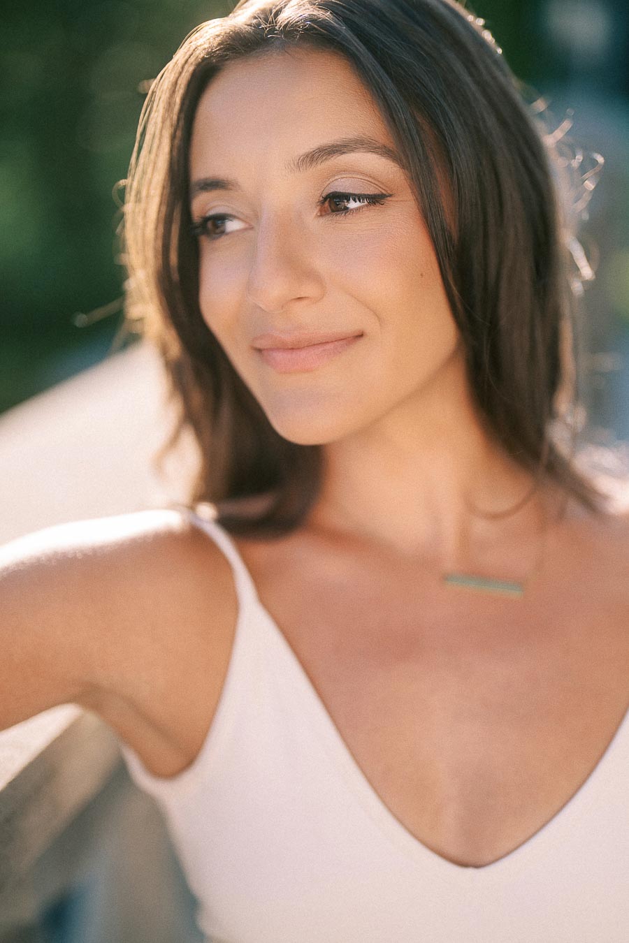Rachel smiles softly in warm sunlight during an outdoor engagement portrait in Aurora, Ontario.
