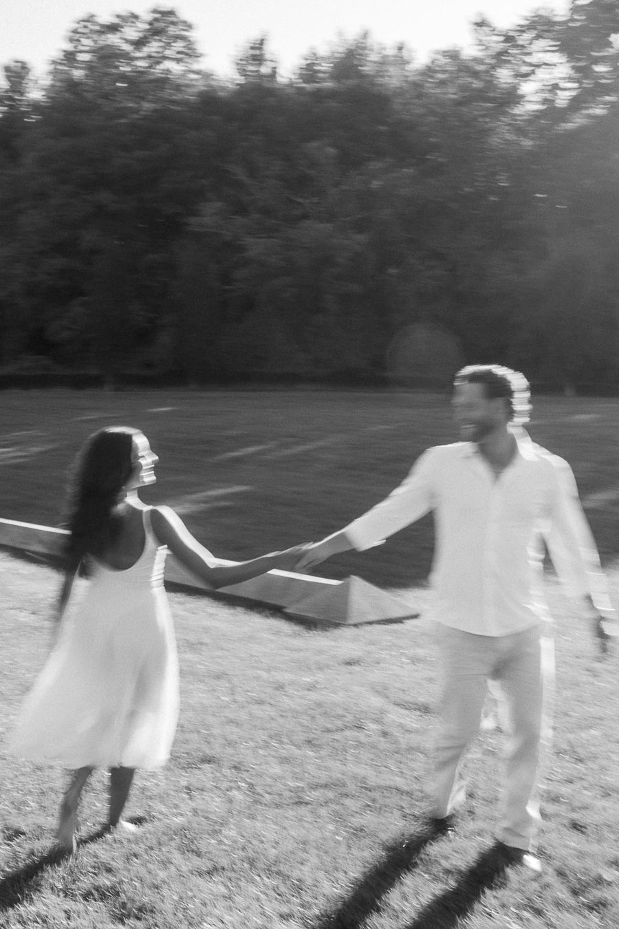 Rachel and Matt hold hands while running across a sunny grassy field in Aurora, Ontario.