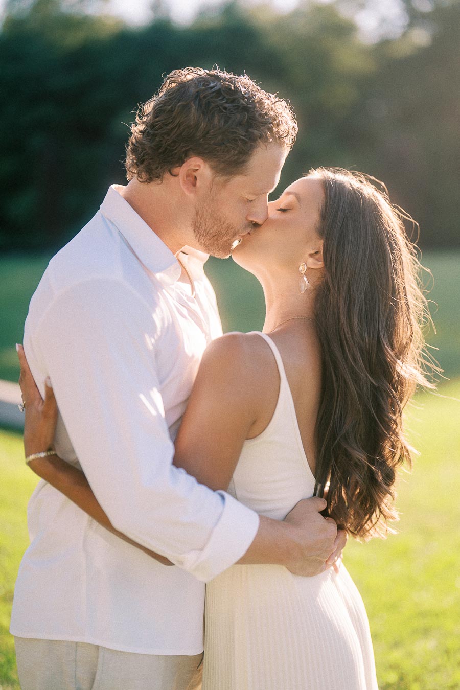 Rachel and Matt kiss while embracing on a sunlit lawn in Aurora, Ontario.