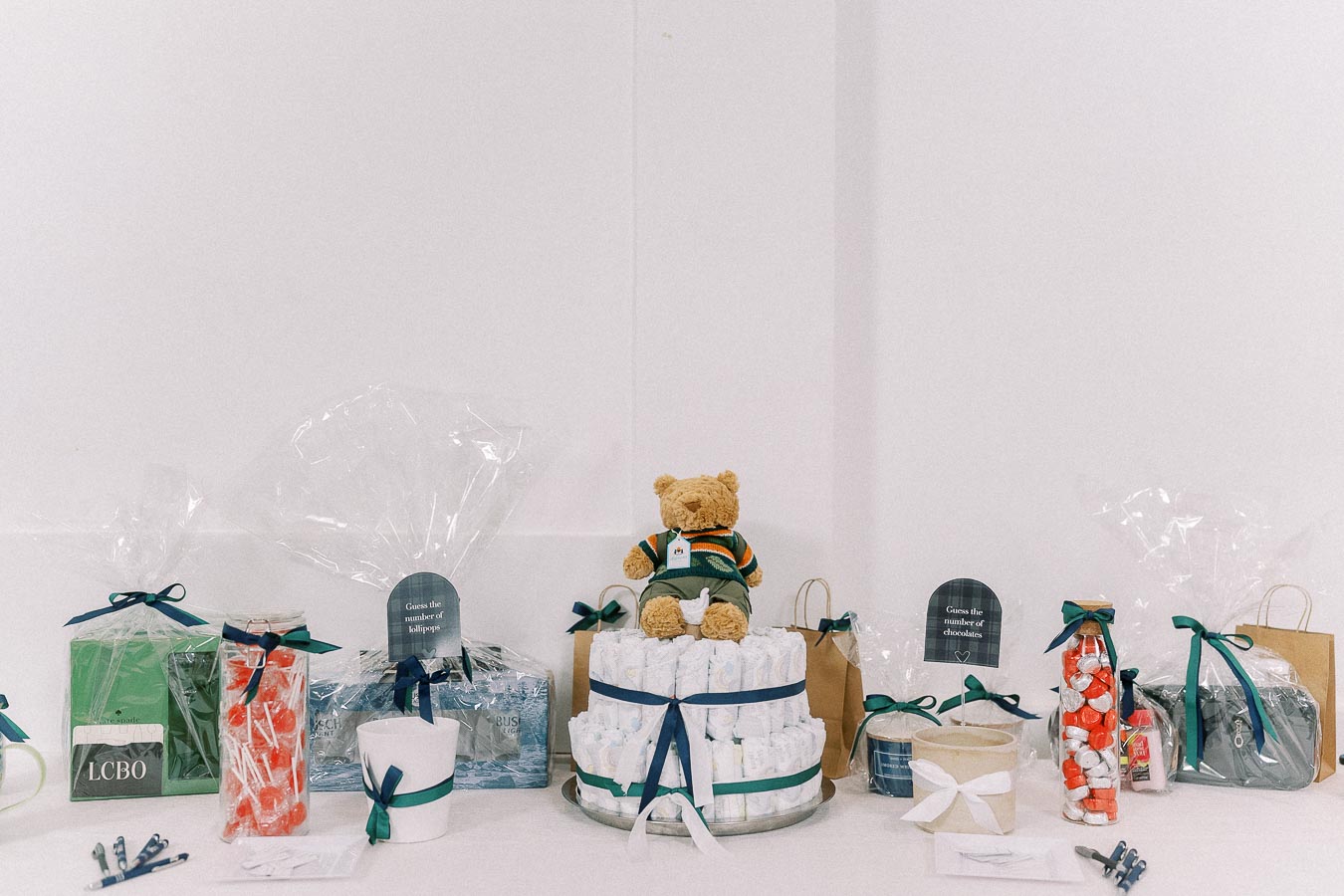 Baby shower gift table with teddy bear diaper cake and wrapped prizes