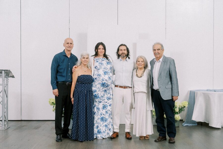 Six adults posing together in formal attire against a white event backdrop