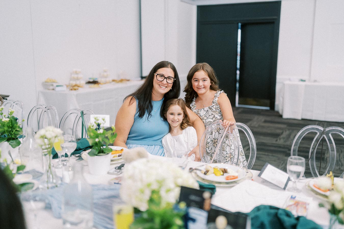 Woman and two girls smiling together at a decorated event table