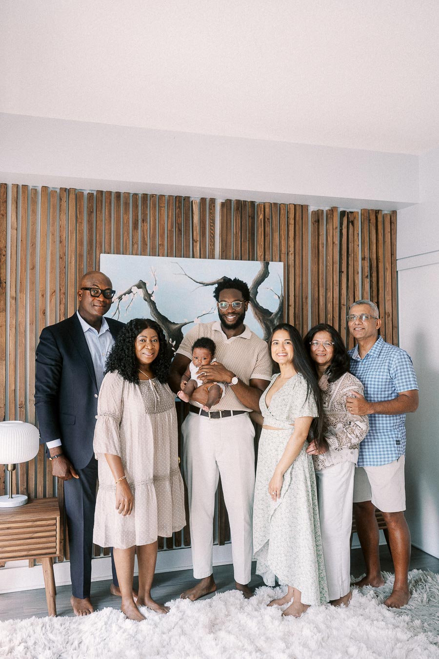 Family members gather around newborn Isabella in a bright Toronto home with a wood slat wall.