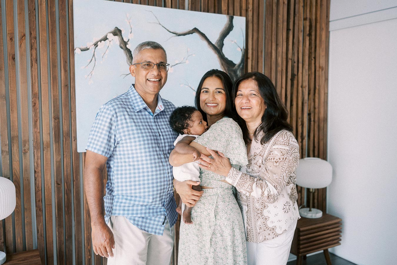 Karina holds Isabella while two family members smile beside them in a Toronto home.