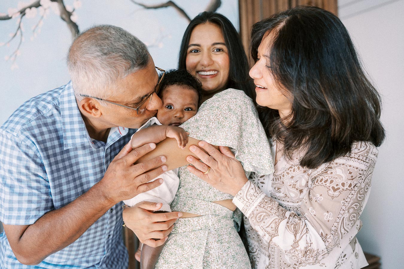 Family members cuddle newborn Isabella as one kisses her cheek at home in Toronto.